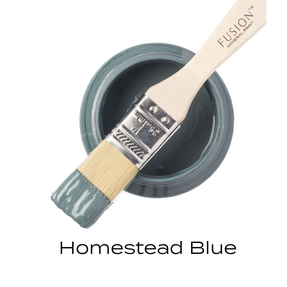 Fusion Mineral Paint brush with a container of Homestead Blue paint on a white background