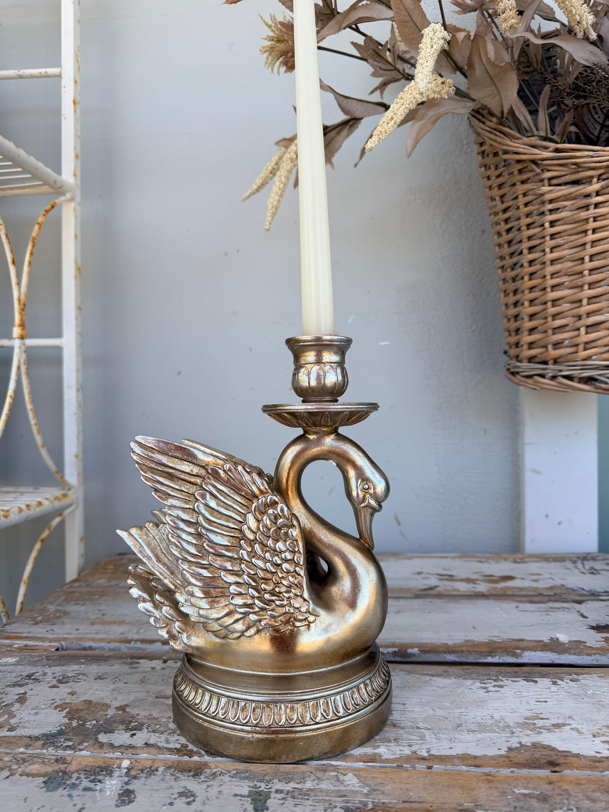 A decorative swan-shaped candle holder in a distressed gold finish,