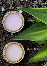 Two cans of paint labeled 'Alexis' and 'Grassmere' on a natural background with leaves. artisan paint