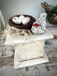 Nest and bird w red beak on rustic plinth white