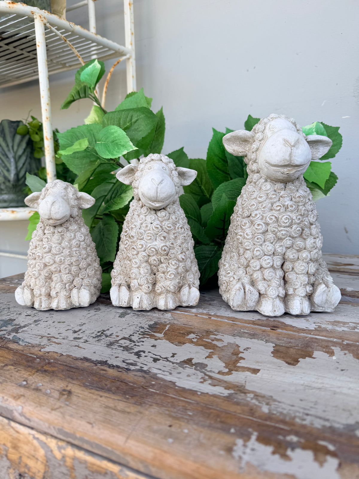 Three textured stone sheep figurines in cream and light gray tones, arranged from smallest to largest. Concrete whitewash look sheep sitting