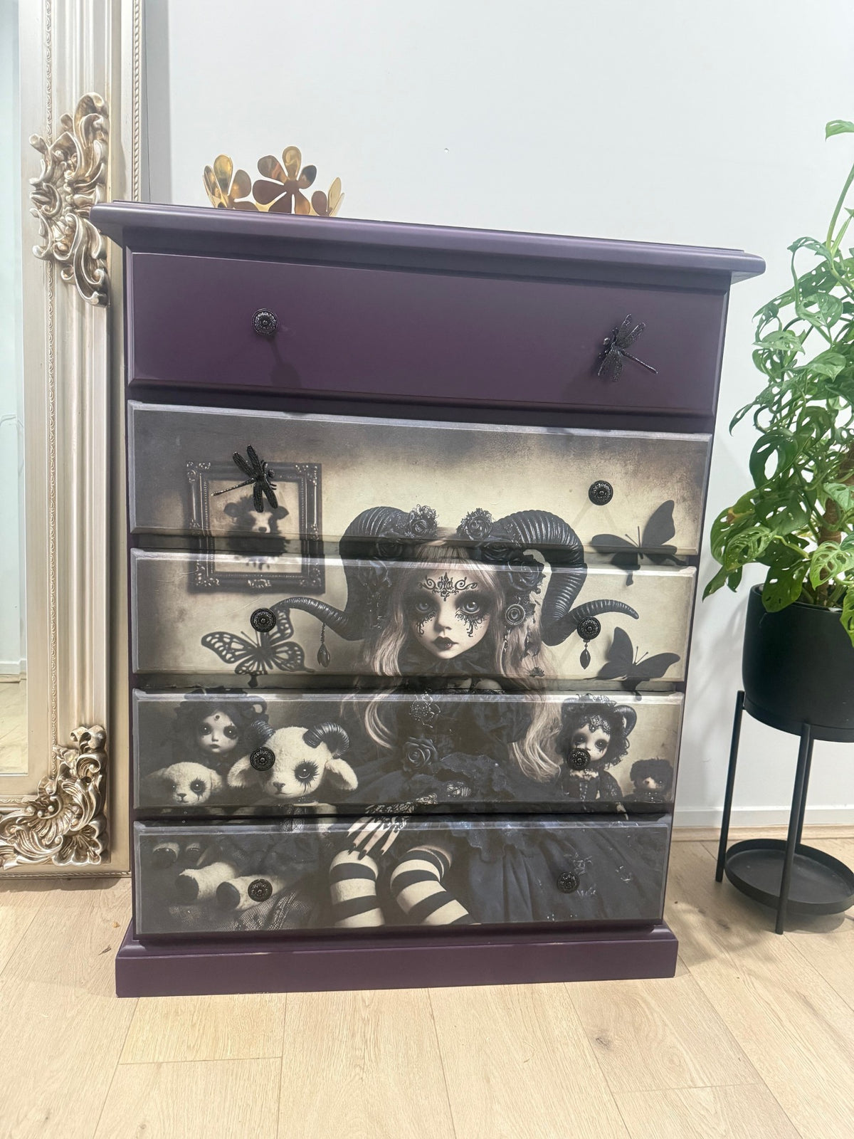 Purple dresser with Gothic-style doll with ram horns surrounded by dolls and butterflies. Dollmakers Curse Mulberry Decoupage Paper