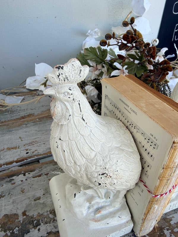 A pair of distressed white rooster bookends holding two vintage-style tan books tied with red string, French Rooster white Book Ends set of 2