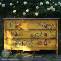 Redesign transfer Large Rosette Aviary. Yellow dresser with floral and bird designs outdoors with white flowers in the background