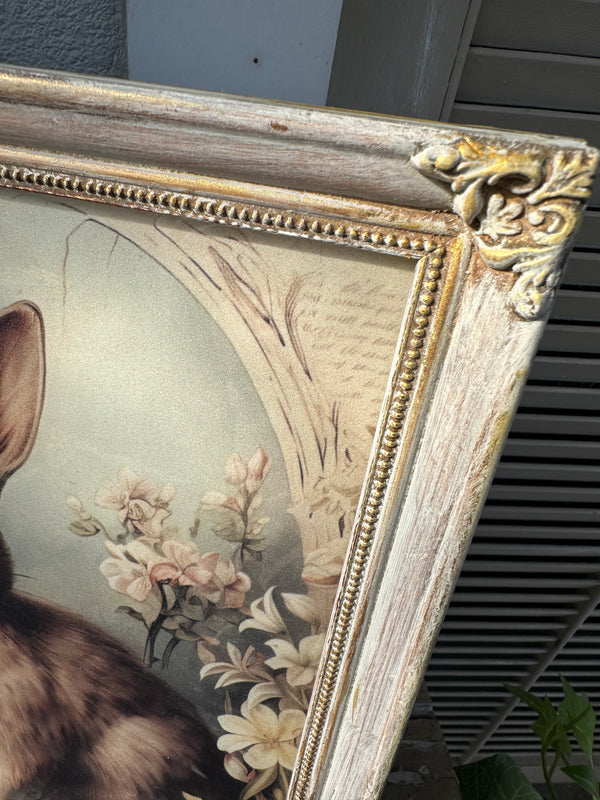 Decorative floral painting with a gold frame on a wall. Bunny Artwork