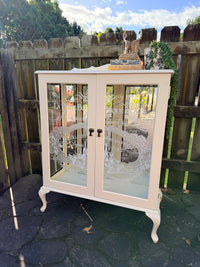 Cabinet with glass doors featuring embossed designs and text. Limestone Cream & White mirrored Display Cabinet with glass shelves