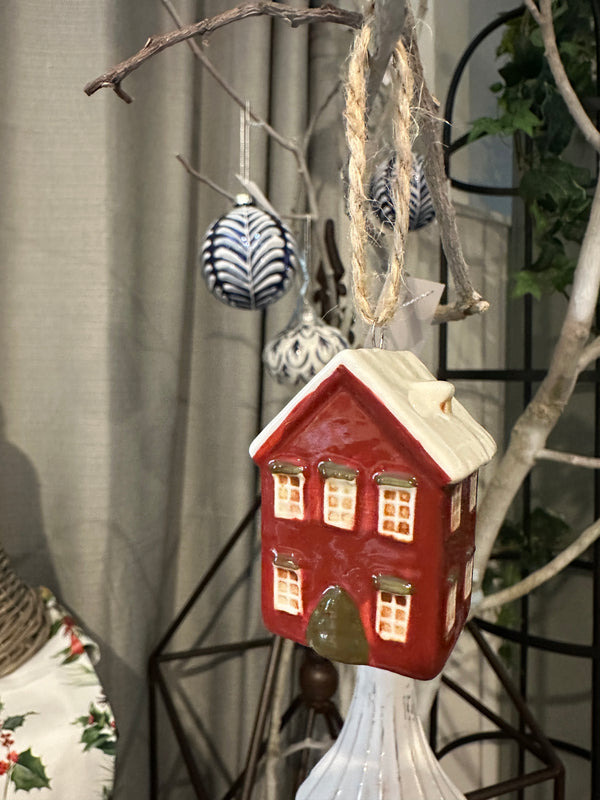 Decorative house-shaped birdhouse on a surface with branches and plants in the background French Country Hanging Mini House