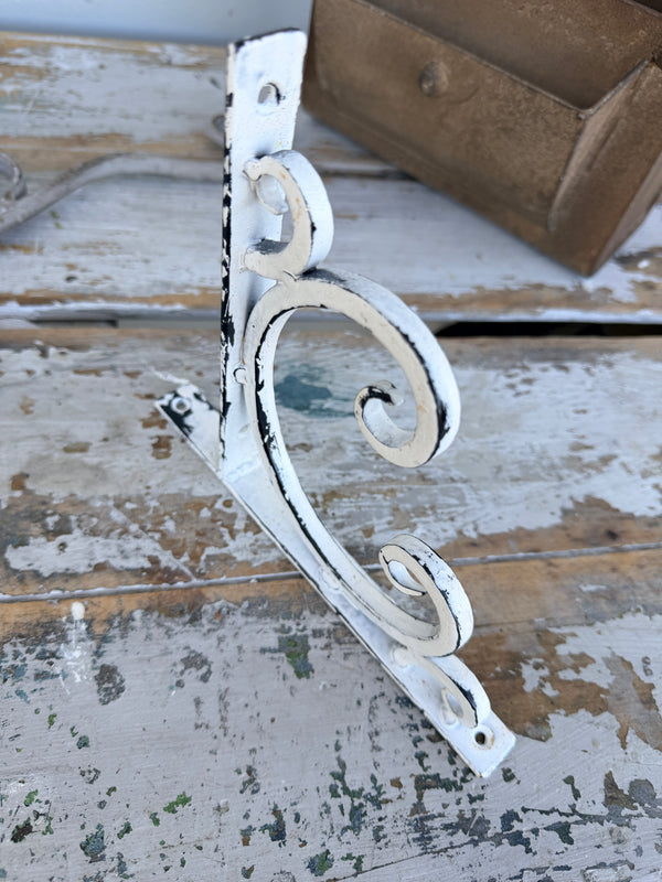 Decorative white metal bracket on a rustic wooden background. Wall or Shelf Bracket White Cast Iron