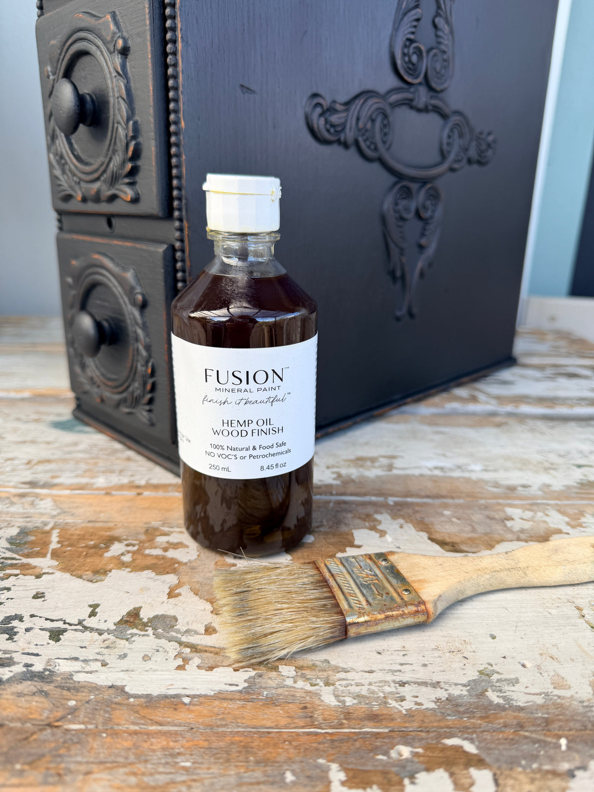 Bottle of Fusion hemp oil finish with a brush on a wooden surface
