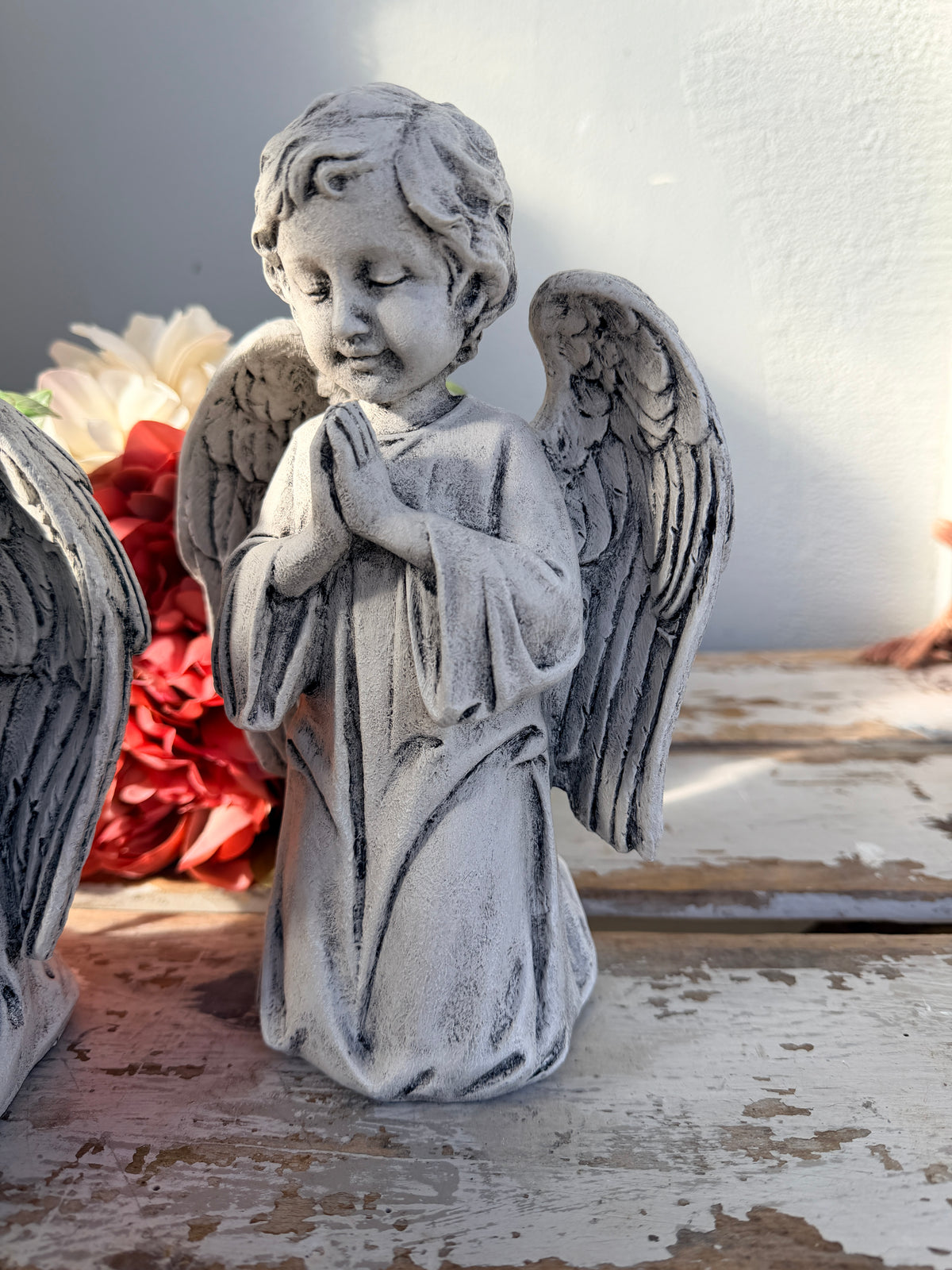A gray stone-look angel figurine with closed eyes, hands together in prayer, and detailed wings. At Peace Statue painted.