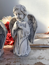 A gray stone-look angel figurine with closed eyes, hands together in prayer, and detailed wings. At Peace Statue painted.