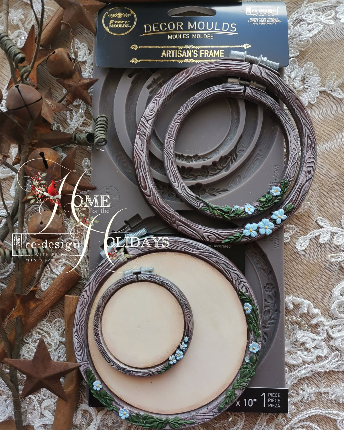Decor Moulds Artisan's Frame set in its retail packaging, featuring two nested rounf frames with a rustic brown bark-like design and small light blue floral accents, displayed on a lace fabric background with decorative autumn elements. Silicone mould DIY with engraved concentric circle patterns and two matching circular metal hoops , like embroidery hoops. Artisan's Frame Mould by Redesign with Prima