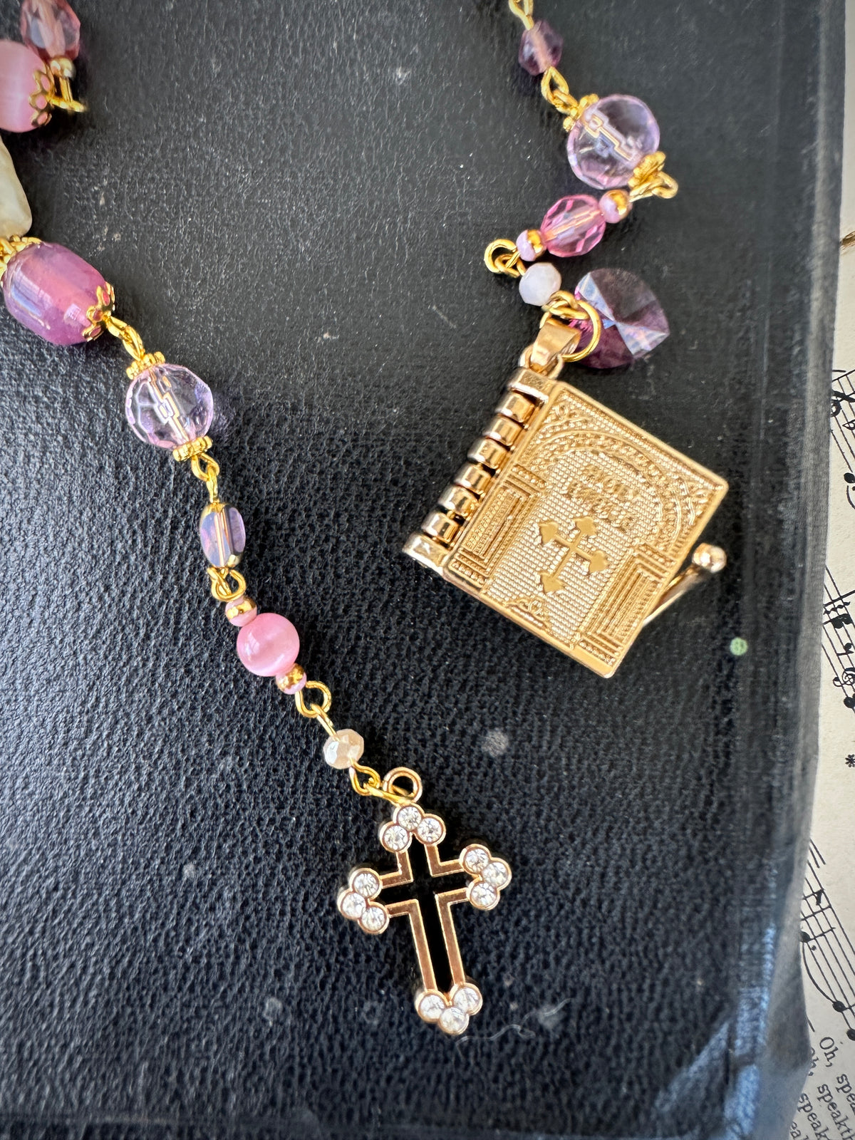 Rosary with pink beads and gold cross on a textured surface
