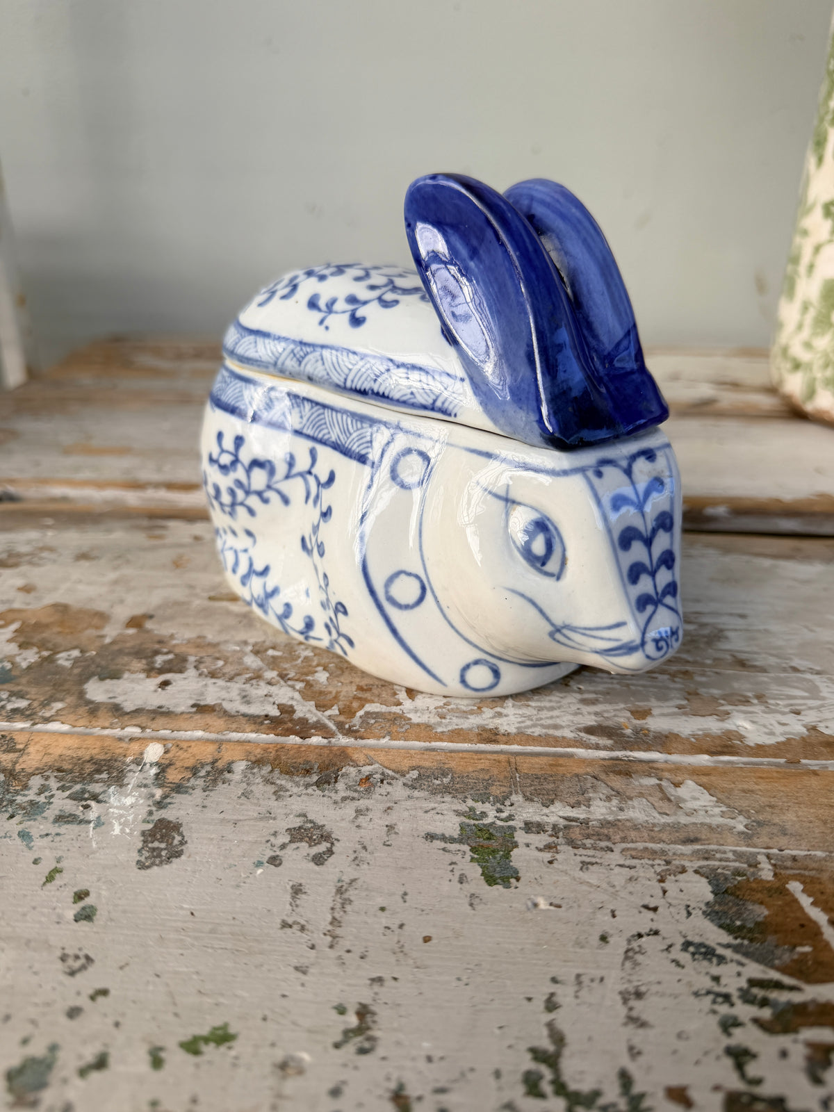 Ceramic rabbit-shaped container with blue and white design on a rustic wooden surface.