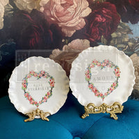 Two decorative plates with floral designs and text on a blue cushion with a floral background. Contours of Grace Mould by Redesign with Prima