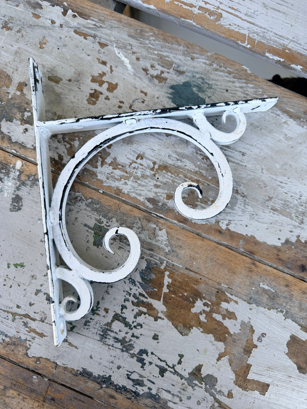 Decorative metal bracket with white paint on a rustic wooden background. Wall or Shelf Bracket White Cast Iron