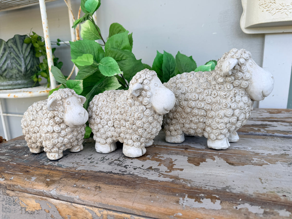 Three small textured sheep figurines in a light beige stone-like finish, arranged from smallest to largest