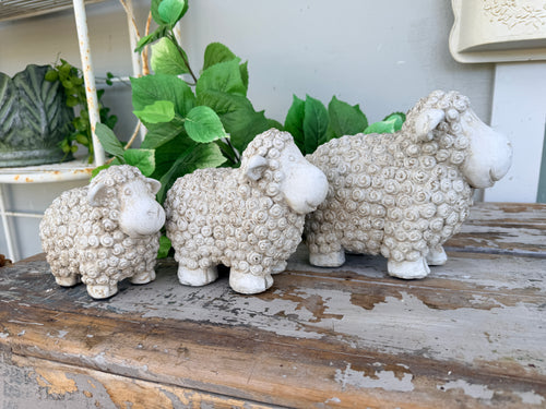 Three small textured sheep figurines in a light beige stone-like finish, arranged from smallest to largest