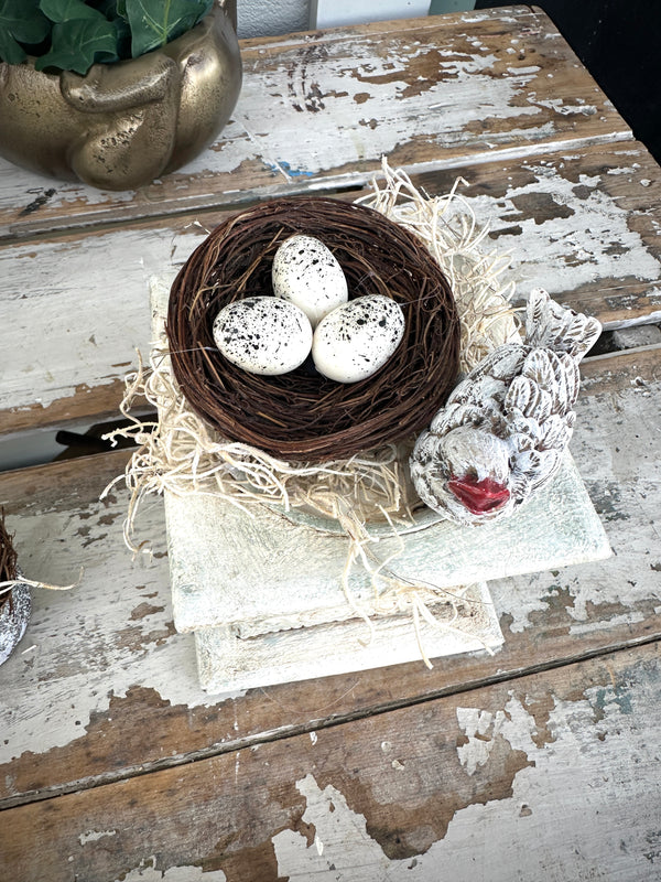 Nest and bird w red beak on rustic plinth white