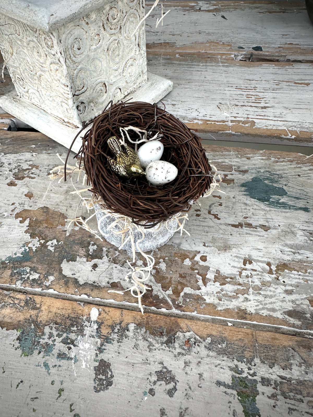 Nest with decorative eggs and birds on a rustic wooden surface