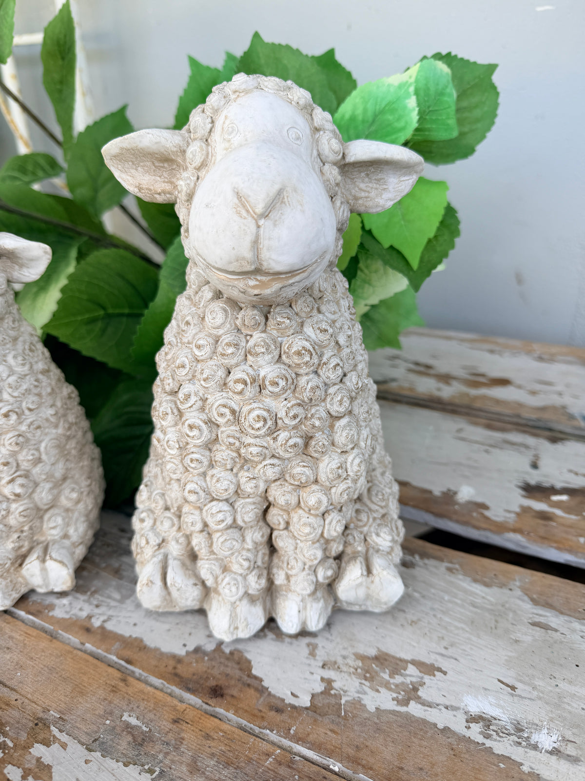 A small decorative sheep figurine with textured curly wool, shown sitting 