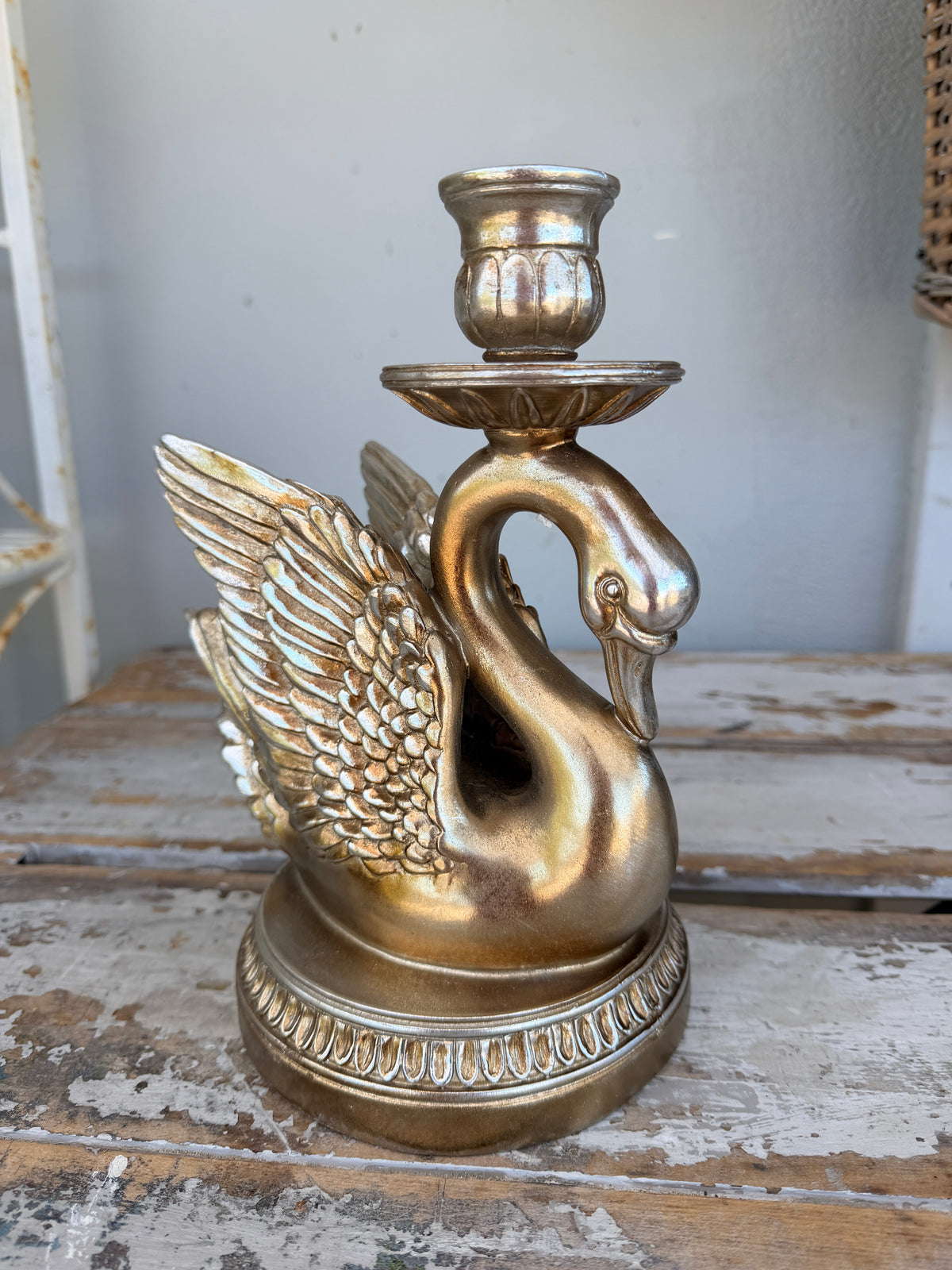 A decorative swan-shaped candle holder in a metallic antique gold finish,