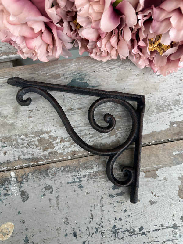 Decorative metal bracket with floral arrangement on a rustic wooden surface. Shelf or Plant Bracket Cast Iron small