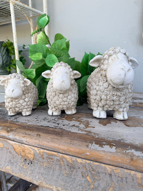 Three small textured sheep figurines in white and cream tones