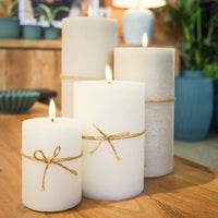 Set of three white candles with twine on a wooden surface, with blurred background