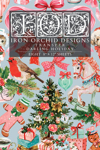 A Christmas-themed transfer sheet featuring a busy holiday pattern with a robin, carousel horse, ornaments, gifts, gingerbread men, bows, and a central title panel reading 'Iron Orchid Designs Transfer Darling Holiday' and 'Eight 8" x 12" sheets'.