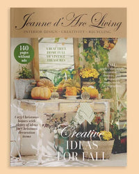 Jeanne d'Arc Living magazine cover featuring a fall-themed interior design photo with pumpkins, flowers, and decorative tables, with the magazine title at the top. Issue 7 2026 Jeanne d'Arc Living Magazine