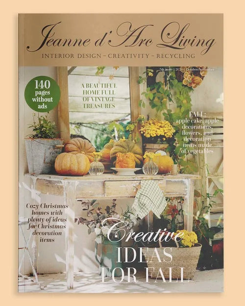 Jeanne d'Arc Living magazine cover featuring a fall-themed interior design photo with pumpkins, flowers, and decorative tables, with the magazine title at the top. Issue 7 2026 Jeanne d'Arc Living Magazine