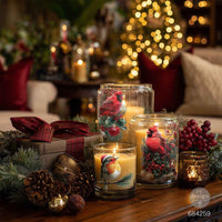 Decorative candles with festive designs on a table in a cozy living room setting. Decorative design of cardinals and berries.  Luxe Transfer Hollywing Cardinal. redesign with Prima Christmas
