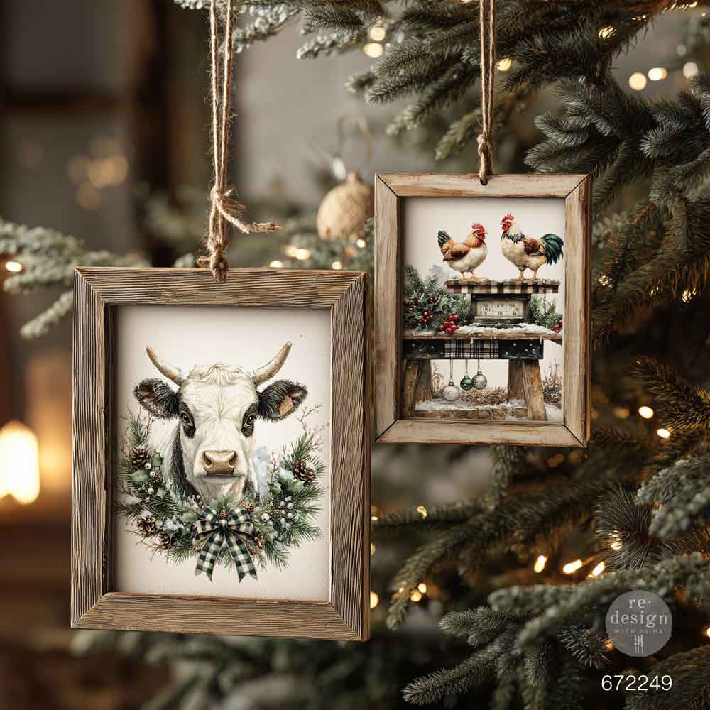 Two framed pictures of a cow and chickens hanging on a decorated Christmas tree. Redesign with Prima transfer middy Rustic Noel
