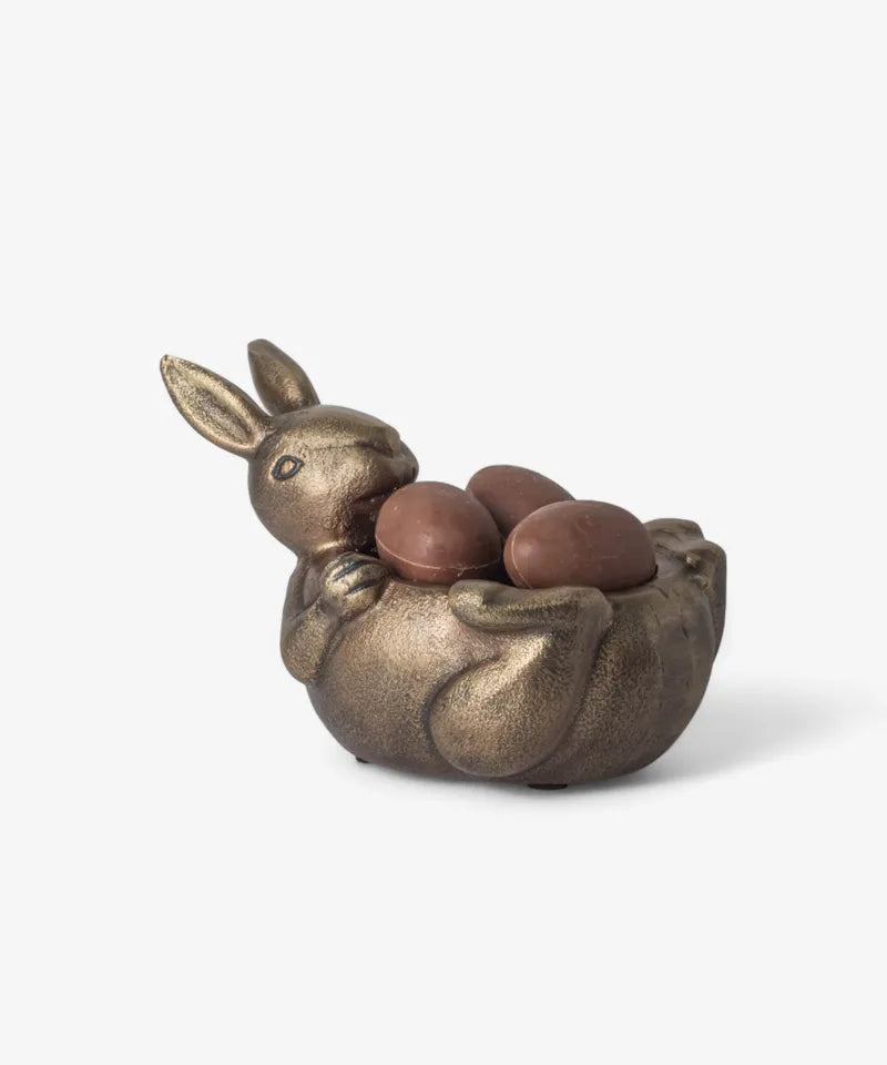 Bronze rabbit sculpture with three eggs on a white background. French Country Rabbit Sweets bowl lying down 