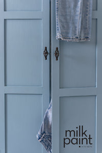 Blue cabinet with denim jeans hanging on a door, featuring the 'milk paint' brand. Skinny Jeans Fusion Milk Paint