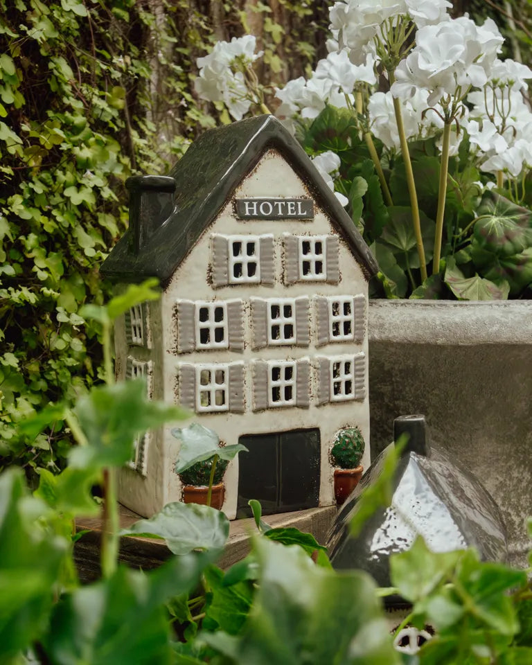 Miniature model of a hotel surrounded by greenery and white . The Village Hotel tea light flowers
