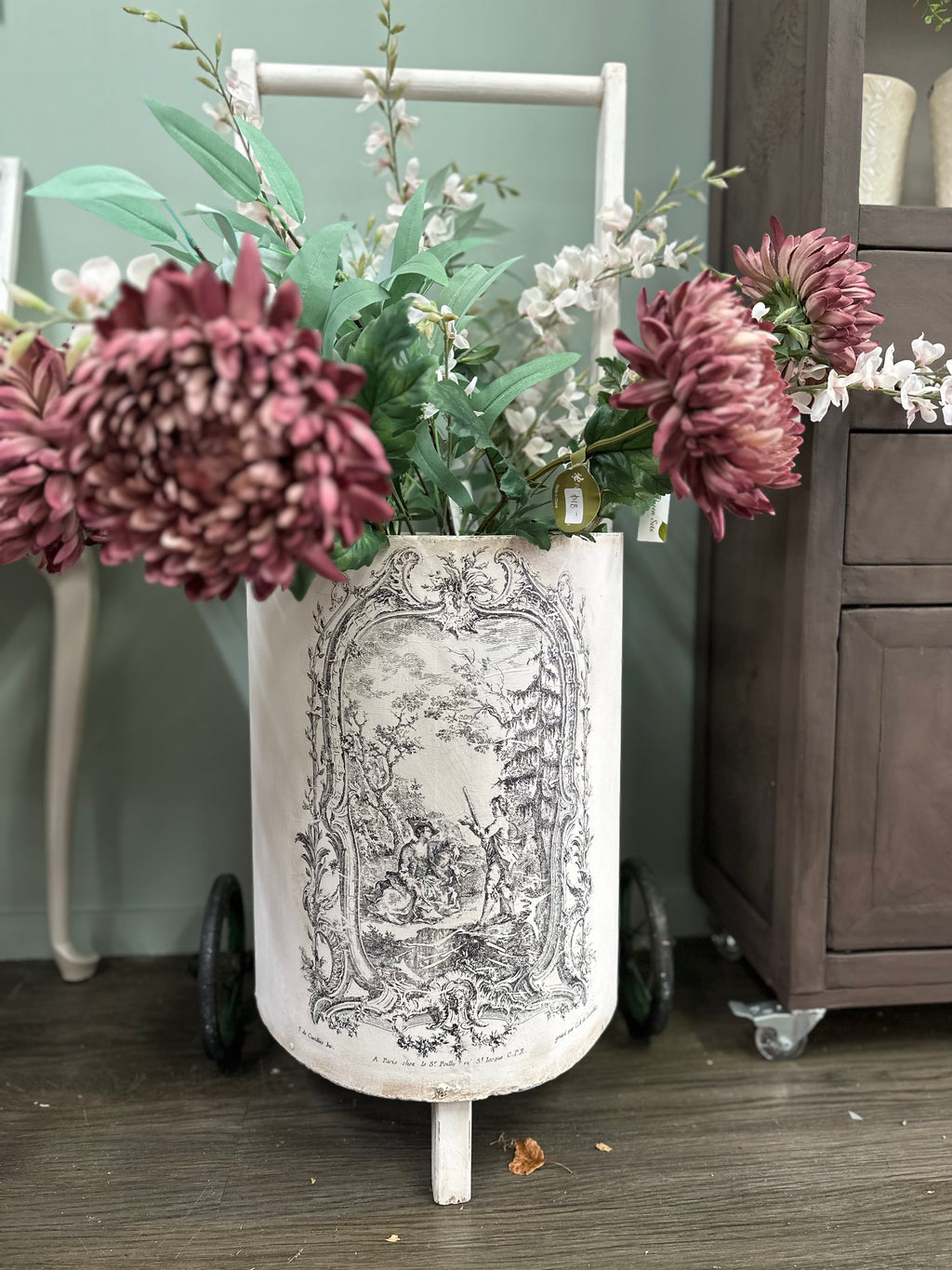 This is a very old trolley and we suggest it is used as a decor and display item only. It is not fit for travelling the pavement. Revamped using the softest of pinks Old Chiffon and our toile paint inlay. She looks perfect filled with flowers.