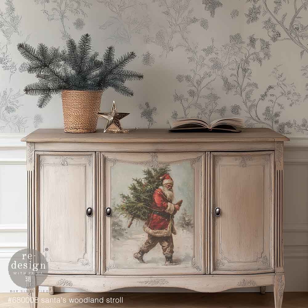 Santa's Woodland Stroll A3 Fiber Decoupage Paper 3 sheets Decorative sideboard with a Christmas design featuring Santa Claus, placed against a floral wallpapered wall.