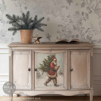 Santa's Woodland Stroll A3 Fiber Decoupage Paper 3 sheets Decorative sideboard with a Christmas design featuring Santa Claus, placed against a floral wallpapered wall.