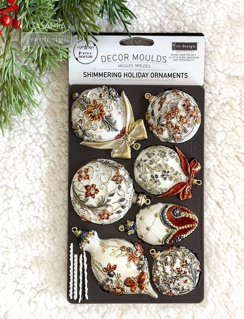 Decorative moulds packaging with Christmas-themed ornaments on a textured surface. shimmering holiday ornaments redesign by prima